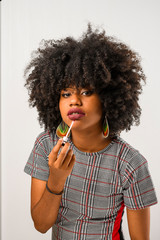 mulher afro aplica batom em seus labios auto cuidado, penteado afro