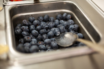 A closeup view of a metal tray container full of blueberries as toppings seen at a local frozen yogurt or ice cream shop.