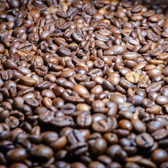 Roasted brown coffee beans lye on the table, front view.