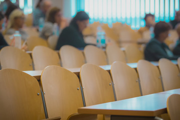 Funky distorted photo of a wooden chair in a classroom or on a seminar, some people sitting around...
