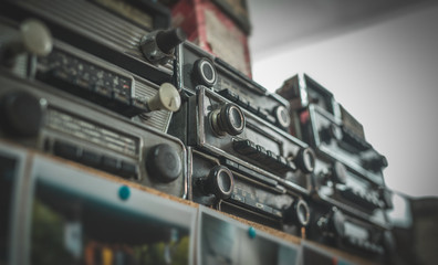 Vintage old timer radios stacked on a shelf. Flea market style collection of a retro car stereos.