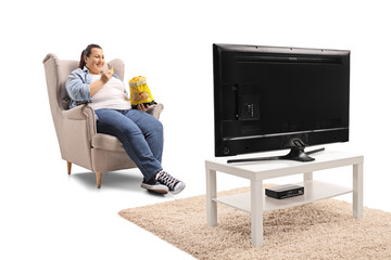 Overweight woman watching tv and eating tortilla chips