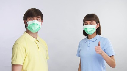young man in protective mask showing distancing to young woman in protection mask