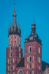 Mariacka bazylika or St. Mary Basilica in Krakow, Poland in beautiful evening light. Visible red brick towers and blue sky.