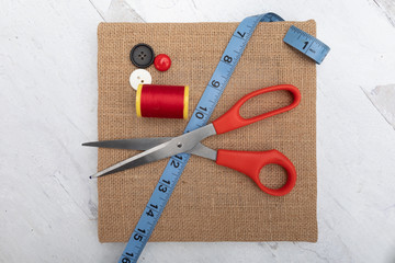 sewing industry background burlap craft square canvas scissors tread blue tape measure assortment buttons 