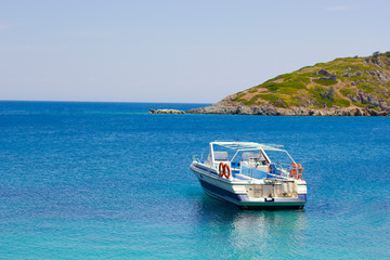 Naklejka na ściany i meble Boat in blue sea on a coastline