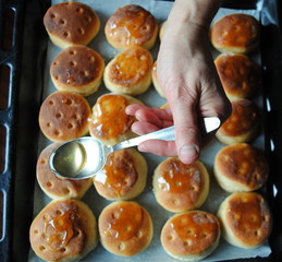 Housewife pours honey over Serbian Traditional baked dough buns called Mladenci.