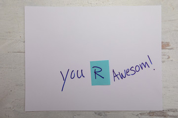 You are awesome sign written on white paper on Woden desk