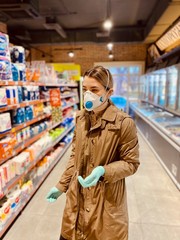 girl in a protective mask and gloves against coronavirus in a supermarket.  beautiful young woman.  grocery store.  Russian girl. Covid-2019.