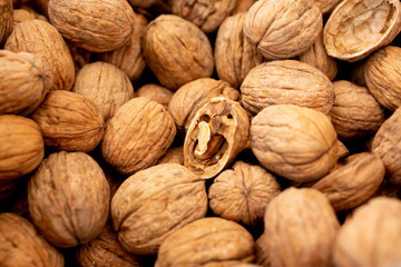 A view of a bin full of walnuts, with one half walnut showing the inside contents of the nut.