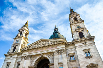 Fototapeta na wymiar Horizontal picture of the front side facade of Saint Stephen's Basilica in Budapest, Hungary with blue sky and clouds above.Roman Catholic basilica built in neoclassical style. Both towers and cupola