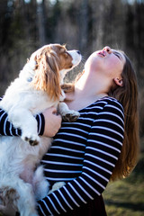 teenage blonde girl with long hair handing small dog in spring warm sun rays 