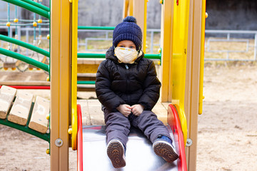 A boy on the Playground in a mask. Health. Coronavirus. Medical mask on the child's face. Security . Pneumonia and the flu. Respiratory protection.