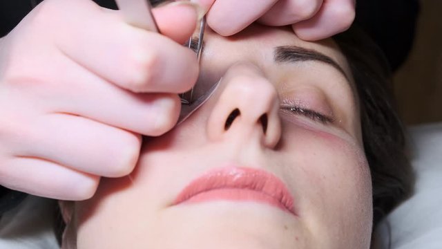 Sticking artificial eyelashes to the woman. Cosmetic procedure