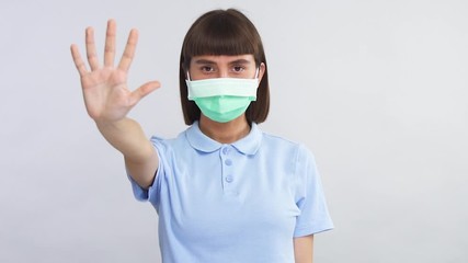 young girl wearing sterile protection mask showing stop sign to camera to isolate herself from society while coronavirus
