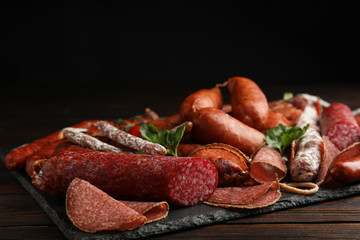 Different tasty sausages on wooden table, closeup