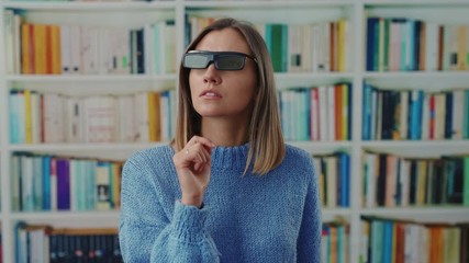 Young modern librarian woman with VR glaases experiencing augmented reality education methods teaching online touch invisible screen working at a library.