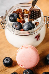 Still life of a snack composed of blueberry yogurt, walnuts, mscaroond and milk in a bottle decorated by hand with rope and lace