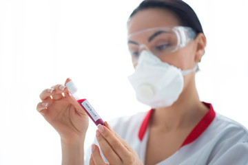 Woman doctor in a mask with a flask with a blood sample. Laboratory research and Covid-19...