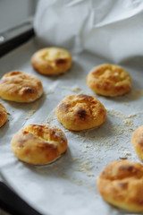 baked cookies on paper on a tray and a wooden board with flour on a table