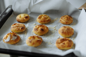 baked cookies on paper on a tray and a wooden board with flour on a table