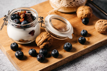 Still life of a snack composed of blueberry yogurt, walnuts, chocolate and milk in a bottle decorated by hand with rope and lace