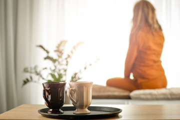 A woman at a sunny window on a wonderful morning behind a wooden table with warm tea