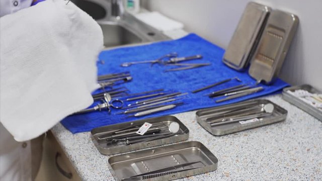 Unidentified nurse is wiping dental instruments after sterilization and washing and putting in steel trayes. Dental clinic