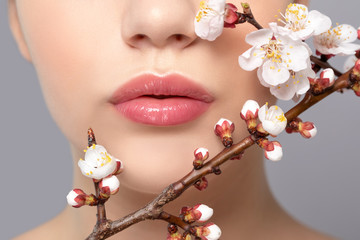 Young girl with beautiful nude make-up and plump lips. Perfect natural lips close up. Near her are...