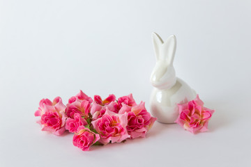 Easter bunny figurine rabbit decor with pink roses on white background.