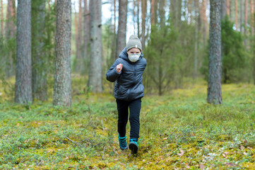 Little boy with a mask run in the forest. Corona virus quarantine