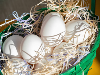 white chicken eggs in a green basket. preparing eggs for Easter.
