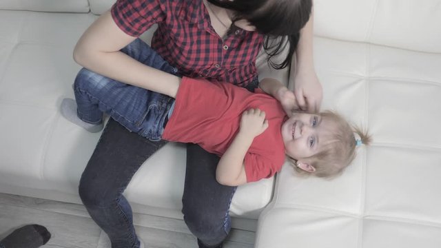 happy family little girl laughs from tickling lifestyle . woman playing with daughter indoors a happy family laughing