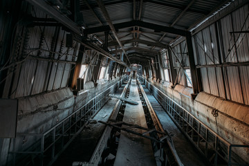 Abandoned cement and concrete factory. Old rusty conveyor in corridor