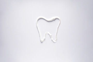 White toothpaste in the form of a tooth on a white background, close-up.