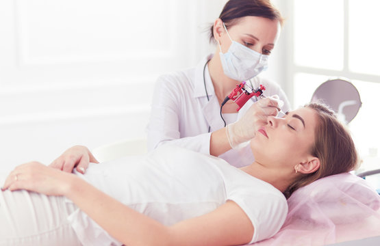 A young girl having red lips permanent makeup, micropigmentation