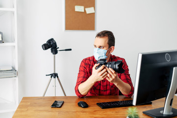 Photographer in medicine mask at the computer