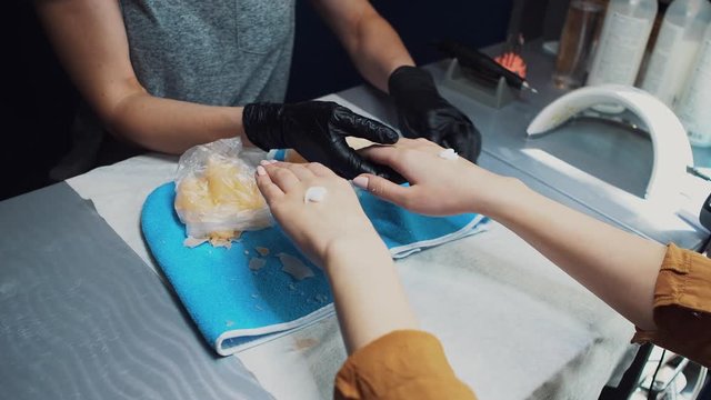 Spa Salon. Manicure. Paraffin Hand Bath. process paraffin treatment. Bowl, additive. Wax bathtub Care. Nail care. Nail artist doing manicure. Professional master putting mitten on hand customer