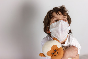 Boy in white tshirt and protective medical mask closed his eyes and afraid with toys monkey on white background. Fight with Coronavirus epidemic concept. Vaccine searching.