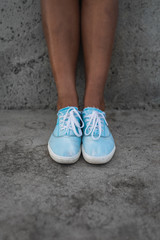 Close up of woman tanned feet, wearing casual blue hipster sneakers keds or shoes 