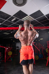 Fototapeta na wymiar Powerful muscular man doing pull up exercise on the horizontal bar