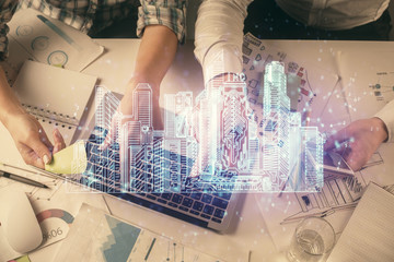 Double exposure of man and woman working together and the buildings hologram drawing. Computer background. Top View. Smart city concept.