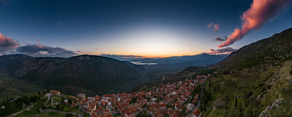 Aerial view of Delphi, Greece, the Gulf of Corinth, orange color of clouds, mountainside with...