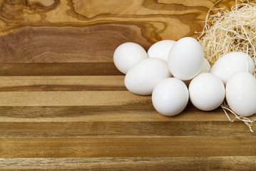 White chicken eggs and broken eggs on wooden board or table.