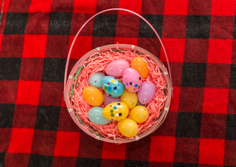 Easter Egg bunny basket sitting on a red plaid blanket filled with colorful eggs