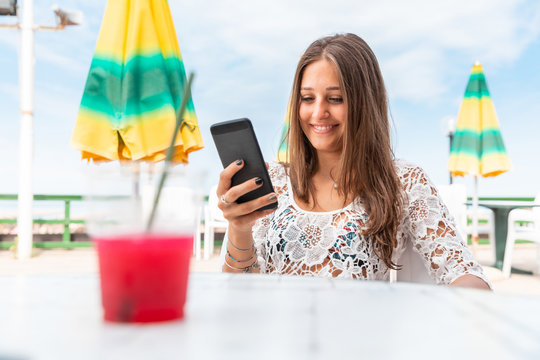 Happy smiling girl with phone and slush at seaside