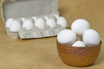 White Eggs isolated in wooden bowl on beige textured background