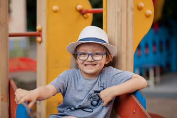 happy cute child with glasses, boy 5 years old on the playground in the summer evening