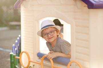 happy cute child with glasses, boy 5 years old on the playground in the summer evening