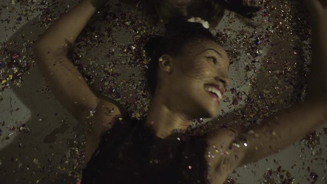Young adult women on floor at party with confetti